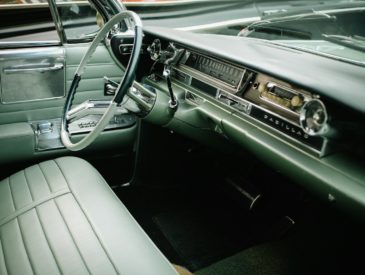 The interior of a vintage Cadillac with green leather seats and a steering wheel