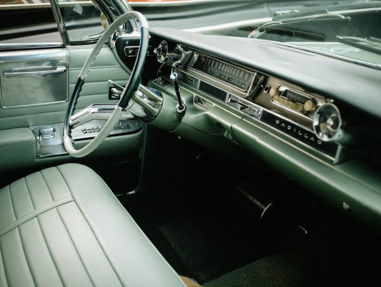 The interior of a vintage Cadillac with green leather seats and a steering wheel