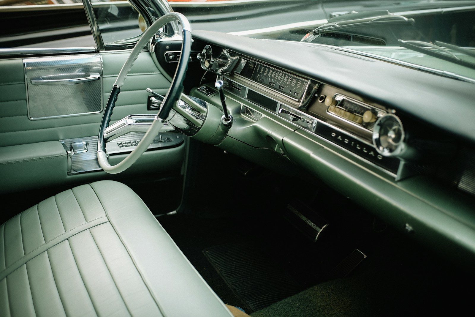 The interior of a vintage Cadillac with green leather seats and a steering wheel